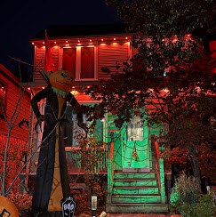 House at night with orange roofline lights and Halloween decorations, one of our installs